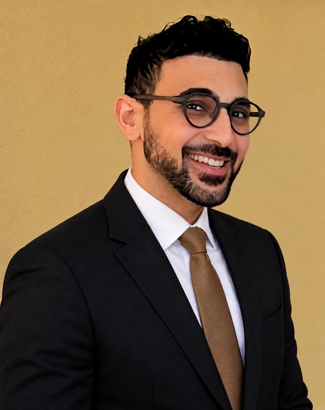 Mina Tawadros smiling in a dark suit and gold tie